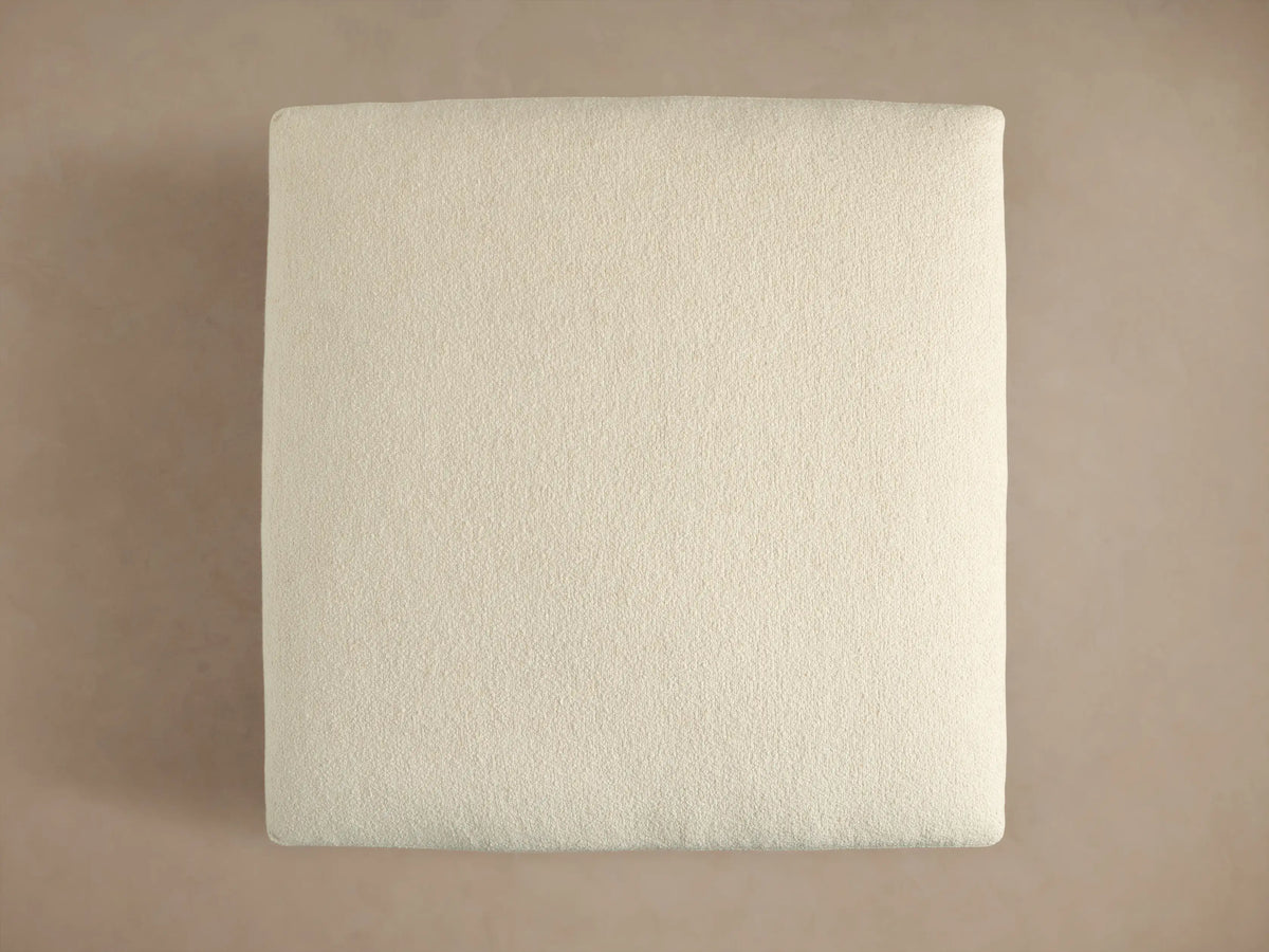 Close-up of Beale Ottoman's textured, off-white fabric on stacked cushions, emphasizing its soft, chunky weave.