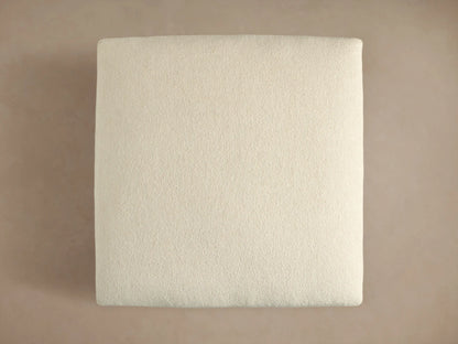 Close-up of Beale Ottoman's textured, off-white fabric on stacked cushions, emphasizing its soft, chunky weave.