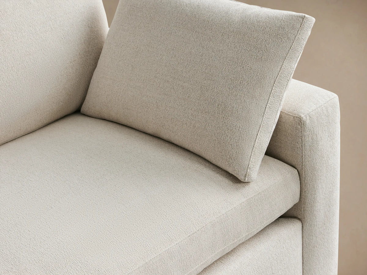 Beale Sofa: Casual light cream 2-seater sofa with block arms, loose back cushions, & one throw pillow on wood floor.