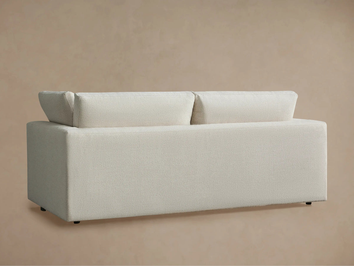 Close-up of Beale Sofa's light cream, textured fabric seat cushion, back cushion, and armrest against a soft beige wall.