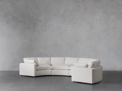 Beale Four-Piece Curved Sectional in off-white fabric, showing its plush seat and back cushions, and low arms. Set against a gray wall.
