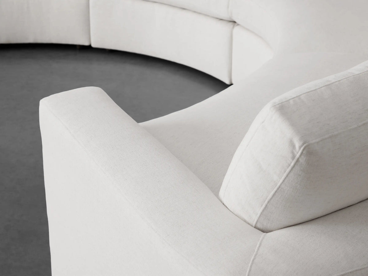 Beale Four-Piece Curved Sectional in off-white fabric, showing its gentle curve and soft cushions against a minimalist gray background.