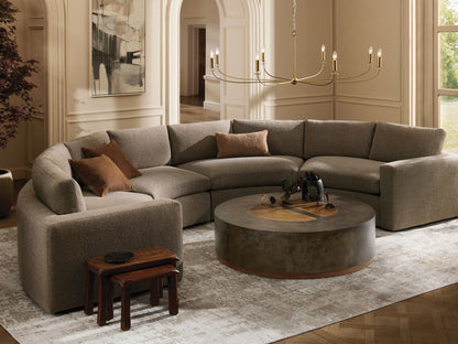 Beale Four-Piece Curved Sectional, U-shaped in textured gray fabric, with brown accent pillows, in a cozy, bright living room.