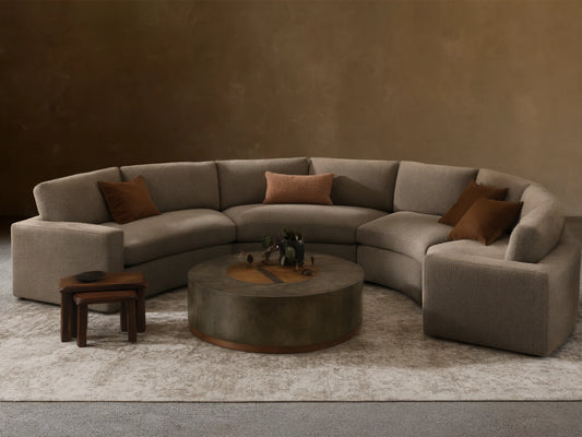 Beale Four-Piece Curved Sectional, U-shaped in textured gray fabric, with brown accent pillows, in a cozy, bright living room.
