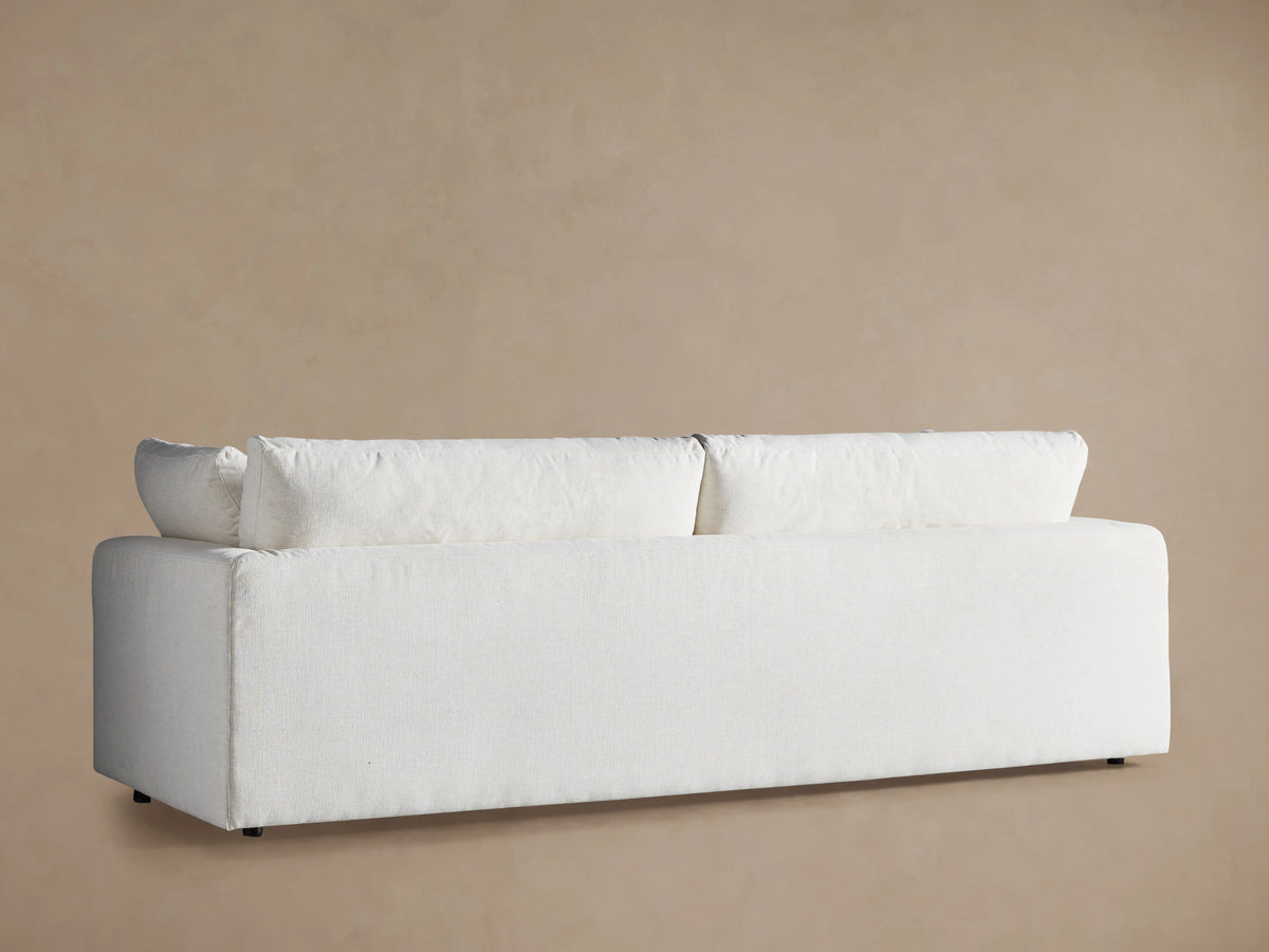 Close-up of the off-white Beale Sofa with textured fabric, showing plush back cushions and a smaller rectangular throw pillow.