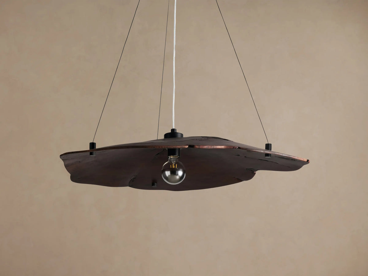 Arruga Chandelier: Dark brown, organic milpa wood dome, suspended by black cables, with a softly glowing bulb.