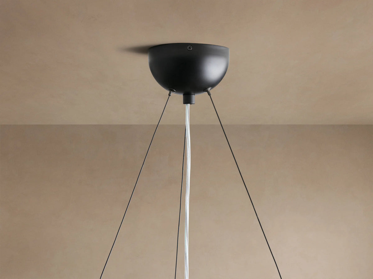 Close-up of Arruga Chandelier's illuminated bulb and dark brown natural milpa wood dome, glowing warmly.