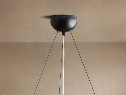 Close-up of Arruga Chandelier's illuminated bulb and dark brown natural milpa wood dome, glowing warmly.